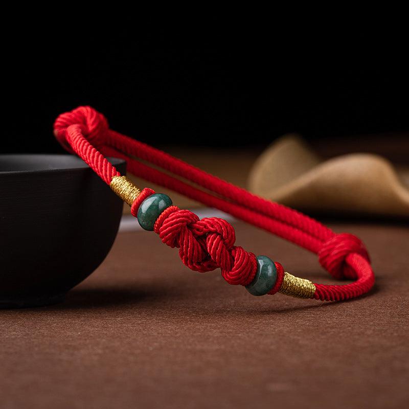 Close-up of the jade beads against the vibrant red rope, highlighting the intricate knotting and cultural symbolism of strength and resilience.